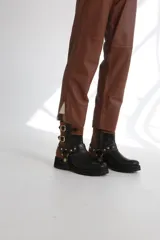 Botas cortas de gamuza color marrón con detalles dorados y hebillas decorativas.