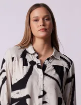 Camisa de manga larga con estampado abstracto en tonos verde y blanco. Cuello con solapa y abertura central con botones. Largo de manga regulable con presilla y botón. Terminación de ruedo anudada opcional.