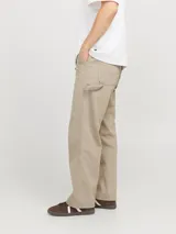 Pantalón jean color arena, de corte amplio, tiro alto y diseño de carpintero con múltiples bolsillos.