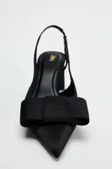 Zapato destalonado negro con tacón ancho y tira trasera. Detalle de lazo en la parte delantera.