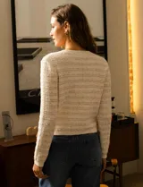 Cardigan de tejido tweed color blanco, marca Catherine Malandrino. Tiene cuello a la base, abertura central con botones perlados, bolsillos simulados en la delantera y bordados en lurex y lentejuelas.
