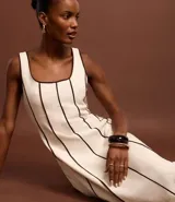 Vestido largo evasé sin mangas, confeccionado en viscolino con 15% de lino. Presenta escote cuadrado en el busto y escote en U en la espalda, con cierre trasero por cremallera. Posee bieses contrastantes.