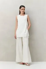 Blusa sin mangas negra de punto suave y fluido, con silueta larga y recta. Presenta botones dorados en los laterales.