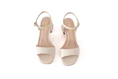 Sandalias de cuero color blanco con taco cuadrado de 5 cm y tira delgada ajustable al tobillo.