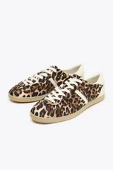 Zapatillas deportivas con estampado animal, suela color caramelo y cordones blancos.