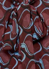 Camisa de manga larga con lazo en el cuello y estampado abstracto en tonos borgoña y celeste.