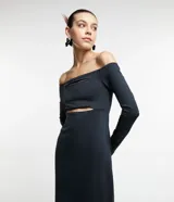Vestido midi de jersey negro, con escote hombro a hombro, mangas largas, aberturas en el busto y tajo en la espalda.