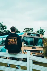 Hoodie negro con estampado colorido en la espalda que incluye palmeras y diseños gráficos.