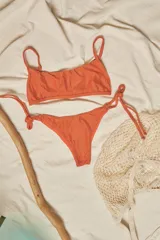 Conjunto de bikini con estampado animal print, compuesto por un corpiño bandeau con breteles finos y una bombacha vedetina con tiras laterales ajustables.