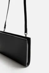 Bandolera negra rectangular con textura grabada. Tiene un compartimento principal con cierre de cremallera, un bolsillo interior con cremallera y un bolsillo simple. El asa de hombro es ajustable y extraíble.