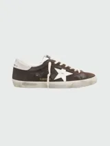 Zapatillas urbanas Golden Goose modelo Super Star Ball Star, color marrón de gamuza con estrella blanca en el lateral, detalles en blanco y suela desgastada.