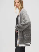 Cardigan tejido de punto con patrón de rombos en degradé de grises y blanco. Tiene corte oversize, mangas largas y cierre frontal con botones.