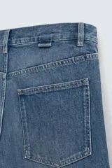 Pantalón de jean azul de tiro medio, corte flare, con cinco bolsillos y cierre frontal con cremallera y botón.