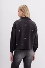 Camisa negra holgada de corte clásico, con cuello camisero, mangas largas con puños y bordados de piedras.