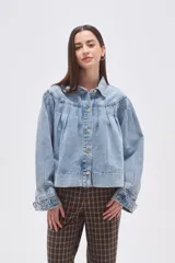 Campera de jean celeste con efecto lavado, caracterizada por mangas abullonadas y frunces en la zona del canesú, cierre frontal con botones metálicos y cuello camisero.