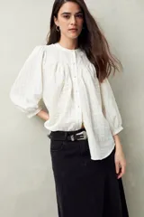 Camisa celeste a rayas verticales, de corte amplio, cuello mao y mangas 3/4 abullonadas.