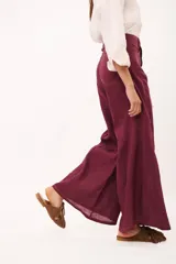 Pantalón de tiro alto, corte ancho y largo, color beige claro con finas rayas verticales en tono oscuro. Presenta cierre frontal con botón y bolsillos tipo jean.