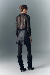 Minifalda negra de cuero con volado en el ruedo, detalles de tachas y cierre lateral.