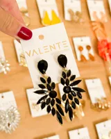 Aretes colgantes grandes de estilo chandelier, con base dorada y múltiples piedras negras facetadas en forma de gota y marquise dispuestas en un diseño floral o de abanico.