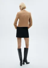 Chaqueta corta de tweed color marrón con cuello redondo, cierre frontal con botones metálicos, cuatro bolsillos de parche y terminaciones deshilachadas.