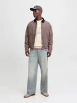 Buzo de manga larga color blanco antiguo (off-white) con cuello redondo y fit holgado. Presenta un estampado frontal con texto que incluye "ORIGINALS STUDIO", "URBAN AESTHETICS" y el número "90" en tonos rosados y dorados.