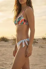 Bikini de dos piezas. El corpiño es tipo triángulo con estampado tropical multicolor y volado en el borde. La bombacha es de corte bajo con nudos ajustables laterales y estampado tie-dye en tonos pastel.