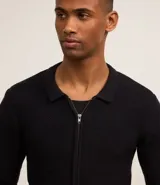 Suéter negro de algodón con textura de cuadros, corte boxy, cuello inglés, cierre con cremallera, mangas largas ajustadas y bajo ajustado.