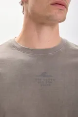 Remera de manga corta color verde militar con estampa frontal con texto y dibujo de una ola.