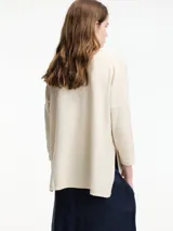 Sweater color crema de corte amplio, con cuello redondo y tajos laterales.