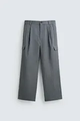Pantalón cargo gris con textura acanalada, corte relaxed fit, cintura elástica con pliegues frontales, bolsillos laterales tipo cargo con solapa, bolsillos frontales y traseros de vivo, cierre frontal con cremallera y botón.