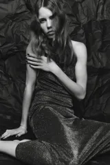 Vestido largo de fiesta confeccionado con hilo metalizado color marrón. Tiene cuello halter con lazada, escote drapeado, espalda descubierta con tira ajustable y cierre lateral con cremallera oculta.