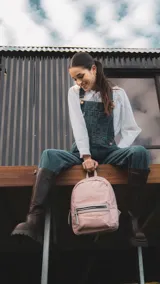 Mochila negra de nylon con bolsillo frontal con cierre y detalles en símil cuero. Tiene asa de mano, correas regulables y bolsillo trasero vertical con cierre. En el interior tiene dos bolsillos con cierre y uno abierto con división.