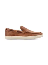 Mocasín de cuero color marrón con cordones decorativos y suela blanca.