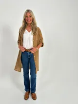 Sobrecamisa color camel de corte recto y largo midi, con cuello camisero, mangas largas con puños abotonados y bolsillos de parche en el pecho.