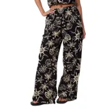 Pantalón de tela negro con estampado de palmeras, soles y estrellas de mar en color beige.