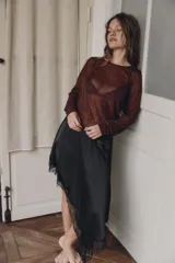 Minifalda negra de satén con corte asimétrico y encaje en el ruedo. Cierre lateral con cremallera oculta.