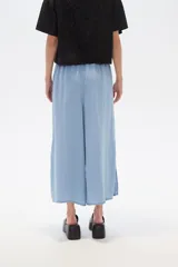 Pantalón capri de denim azul con cintura elástica y aberturas laterales en el ruedo.