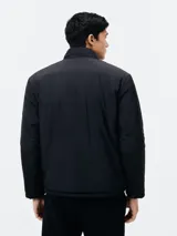 Campera acolchada reversible, color negro con interior beige, cuello mao y cierre frontal con cremallera.