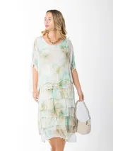 Vestido dos en uno confeccionado en seda italiana, con capa superior de calce amplio y falda con volados que aportan movimiento. Incluye forro en algodón elastizado.