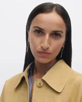 Aros colgantes dorados con forma de argolla y barra vertical de circonitas blancas.