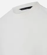 Remera de mangas cortas color crema, confeccionada con 50% algodón y 50% poliéster, con cuello redondo y tejido texturizado.