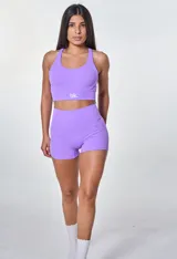 Conjunto deportivo violeta compuesto por un top con breteles cruzados en la espalda y logo "bk." en el frente y un short de calce ajustado.