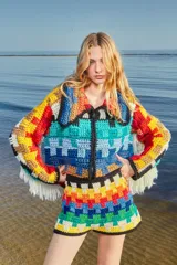 Cardigan tejido a crochet con patrón de cuadrados multicolores, cuello con solapa, cierre frontal con cremallera y flecos en las mangas.