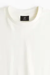 Remera color crema de corte holgado, con cuello redondo y mangas cortas.