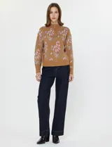 Buzo de tejido de punto color camel con diseño floral en tonos rosados y grises. Presenta cuello alto con cierre frontal parcial.