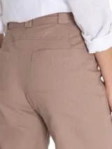 Pantalón beige de corte recto, con cinturón y amplios bolsillos laterales.