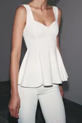Top blanco de tejido elástico, con escote redondo, tirantes anchos y bajo peplum.