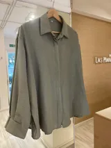 Camisa color beige de lurex, de corte holgado y mangas largas con puños abotonados.