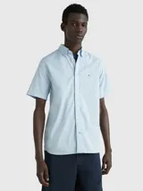 Camisa celeste de mangas cortas, confeccionada en popelín de puro algodón. Tiene cuello abotonado, bajo redondeado y logo de Tommy Hilfiger bordado en el pecho.