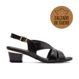 Sandalia de cuero charol negro con tiras cruzadas y hebilla dorada. El taco es cuadrado con detalle dorado en la parte superior.